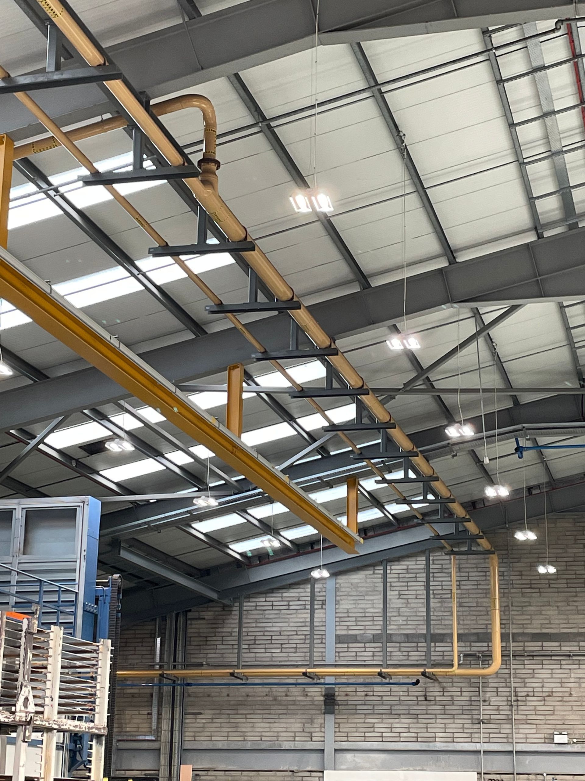 Warehouse interior with metal beams, yellow pipes, and overhead lighting.