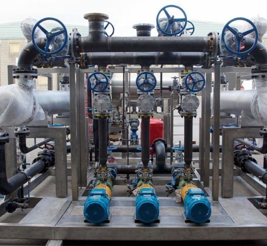Industrial piping system with multiple valves, pumps, and gauges, likely for fluid control.