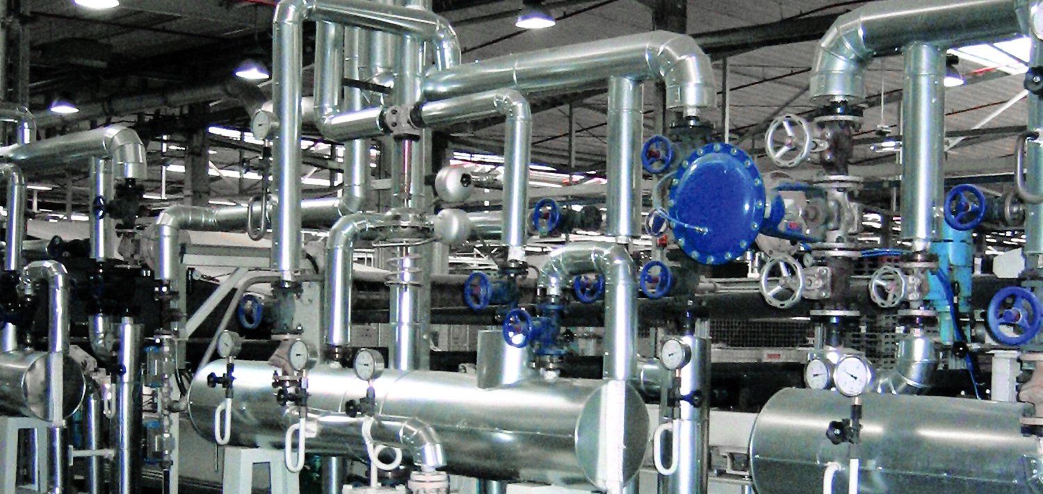 Complex network of metal pipes and valves in an industrial setting.