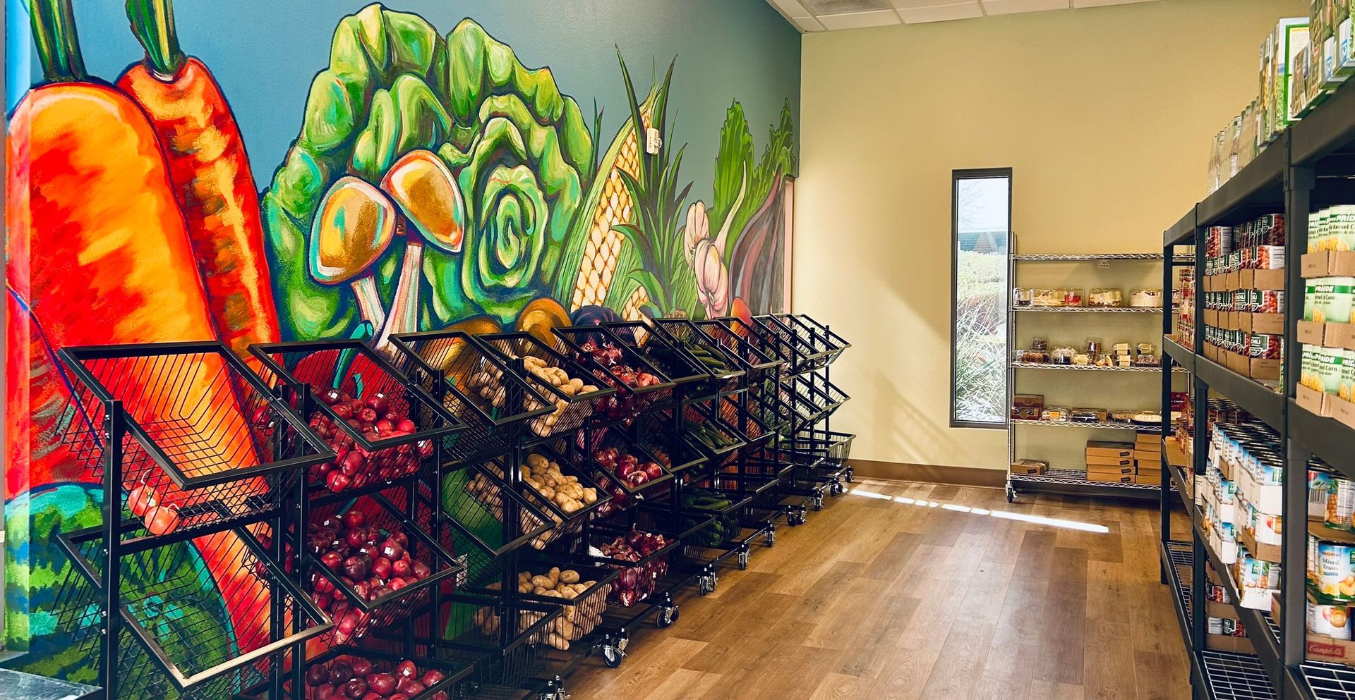 Produce store interior with mural of vegetables and stacked display shelves.