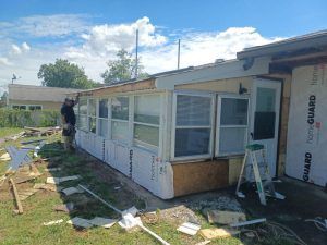 A man is standing in front of a house that is being remodeled.