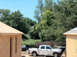 A white truck is parked in front of a house under construction.