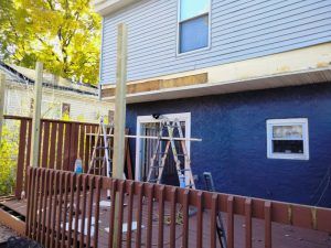 A blue house with a wooden deck in front of it.