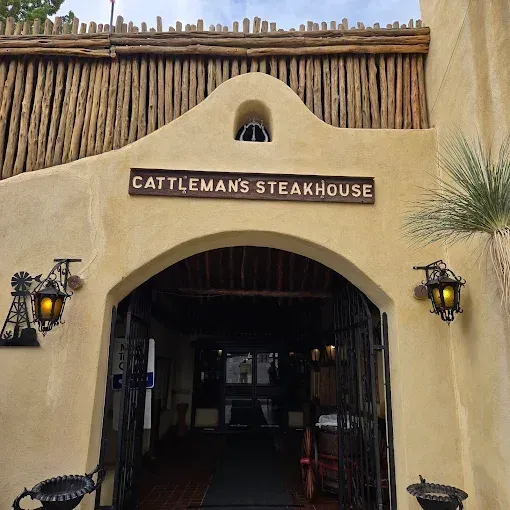 Cattleman's Steakhouse entrance with archway, sign, lanterns, and wooden fence.