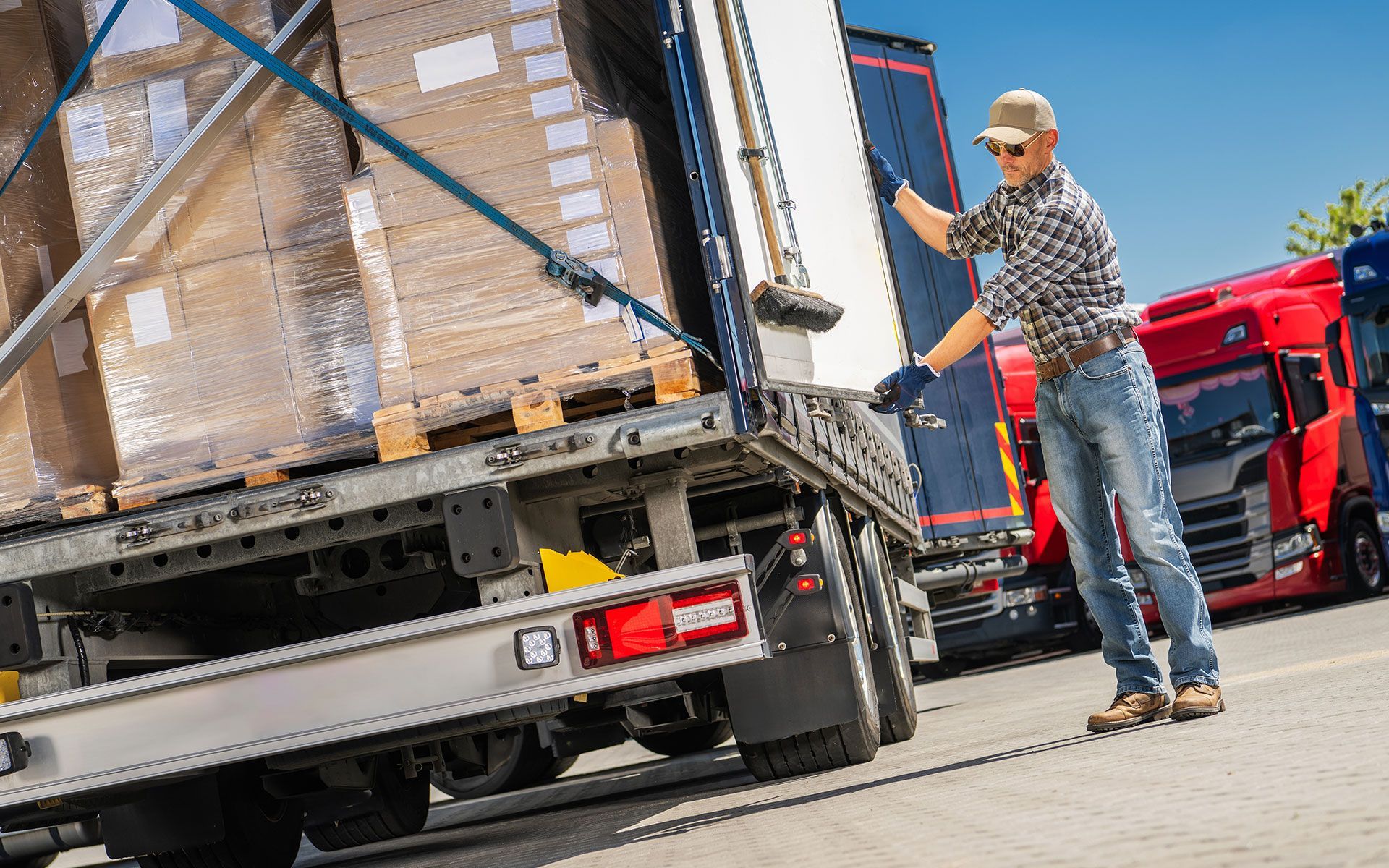 Truck driver secures cargo in truck trailer at loading dock.