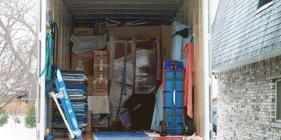 Inside of a packed moving truck, filled with boxes, furniture, and other belongings.