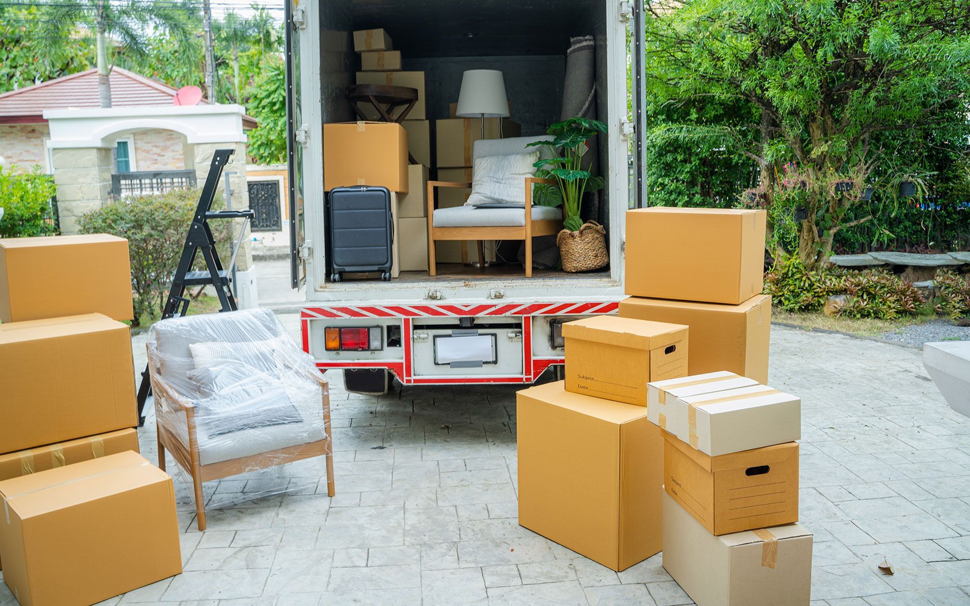 Moving truck loaded with boxes and furniture in a driveway.