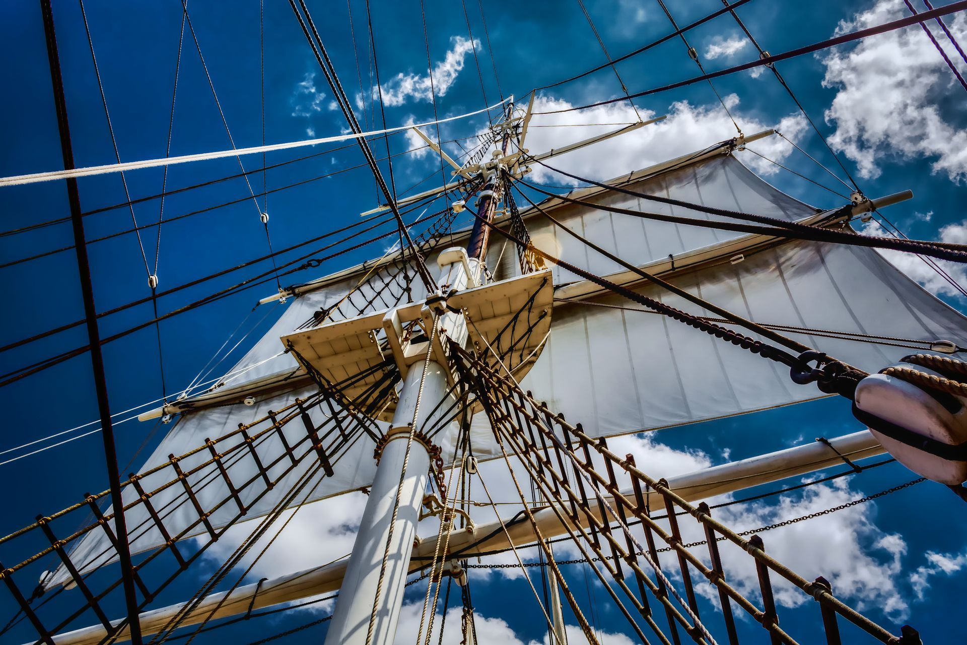 Looking up at the mast of a sailboat with a blue sky in the background