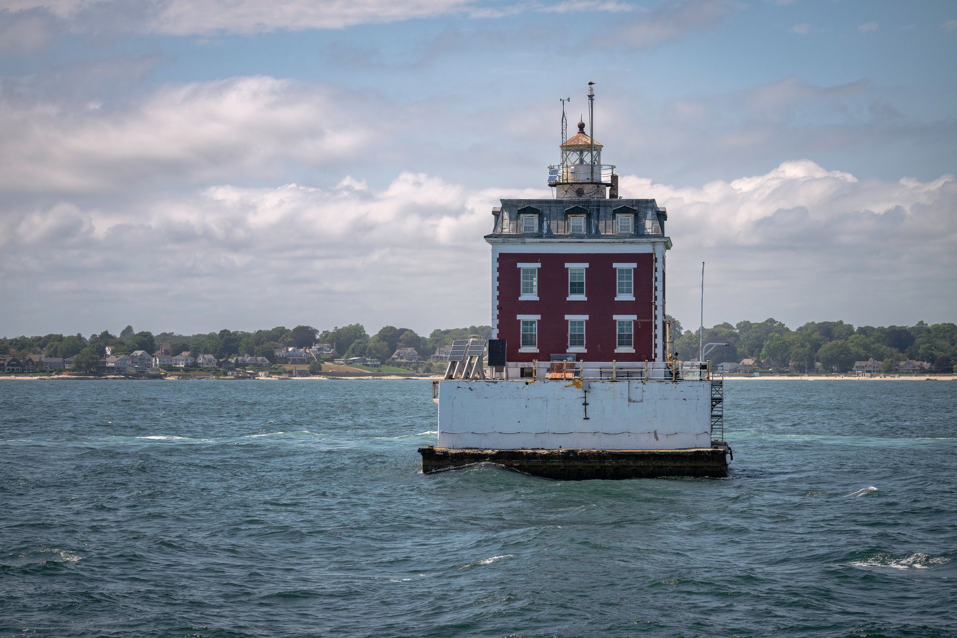 A red and white lighthouse is in the middle of the ocean