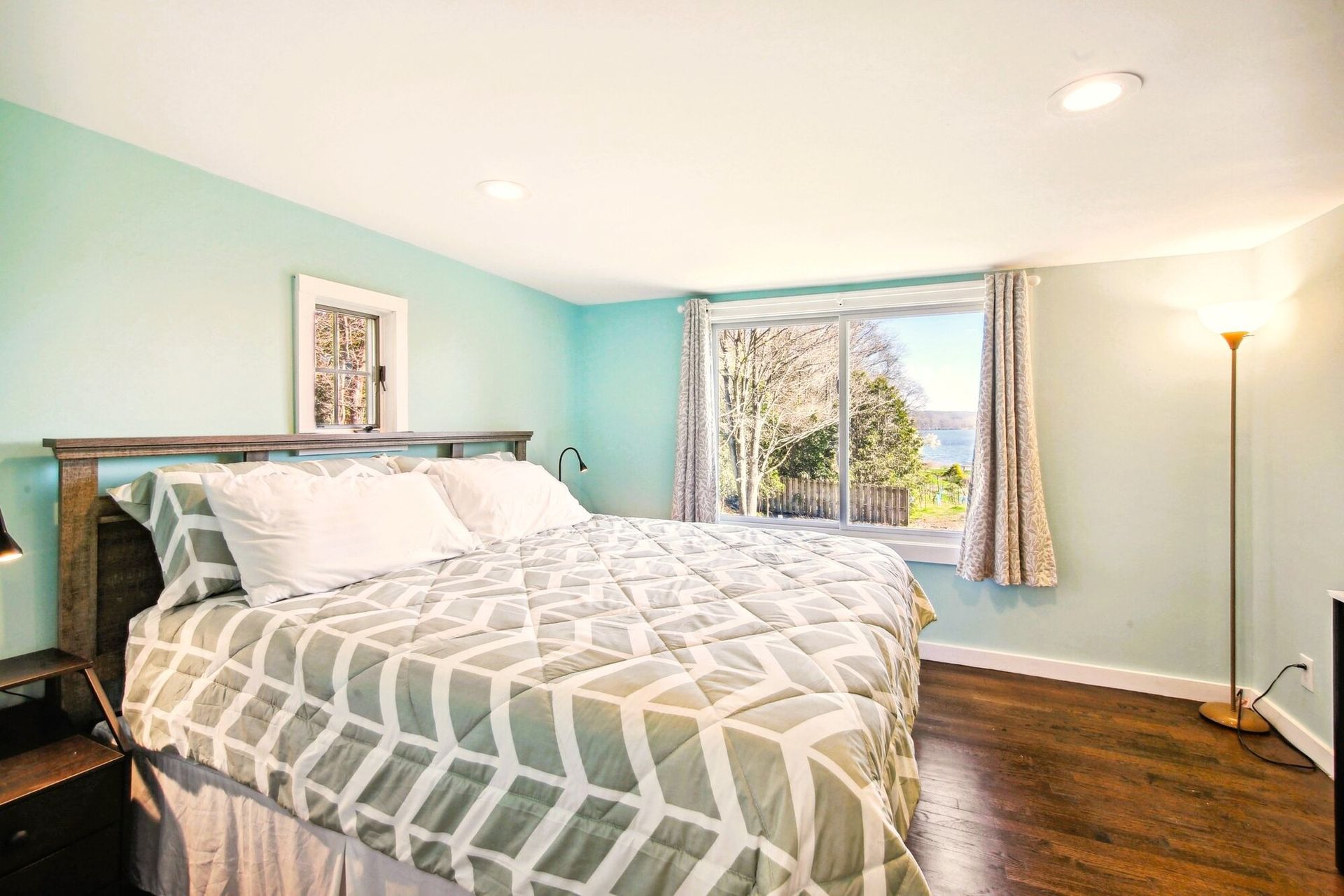 A bedroom with a king size bed and a large window.