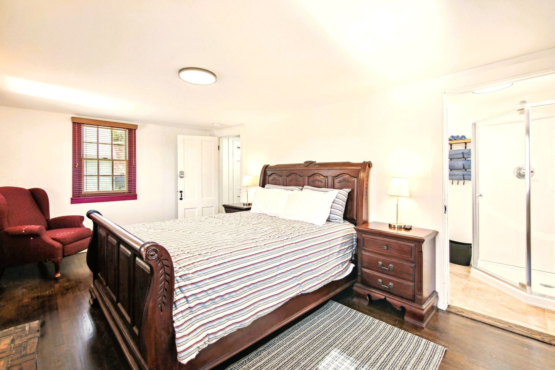 A bedroom with a king size bed , nightstand , chair and window.