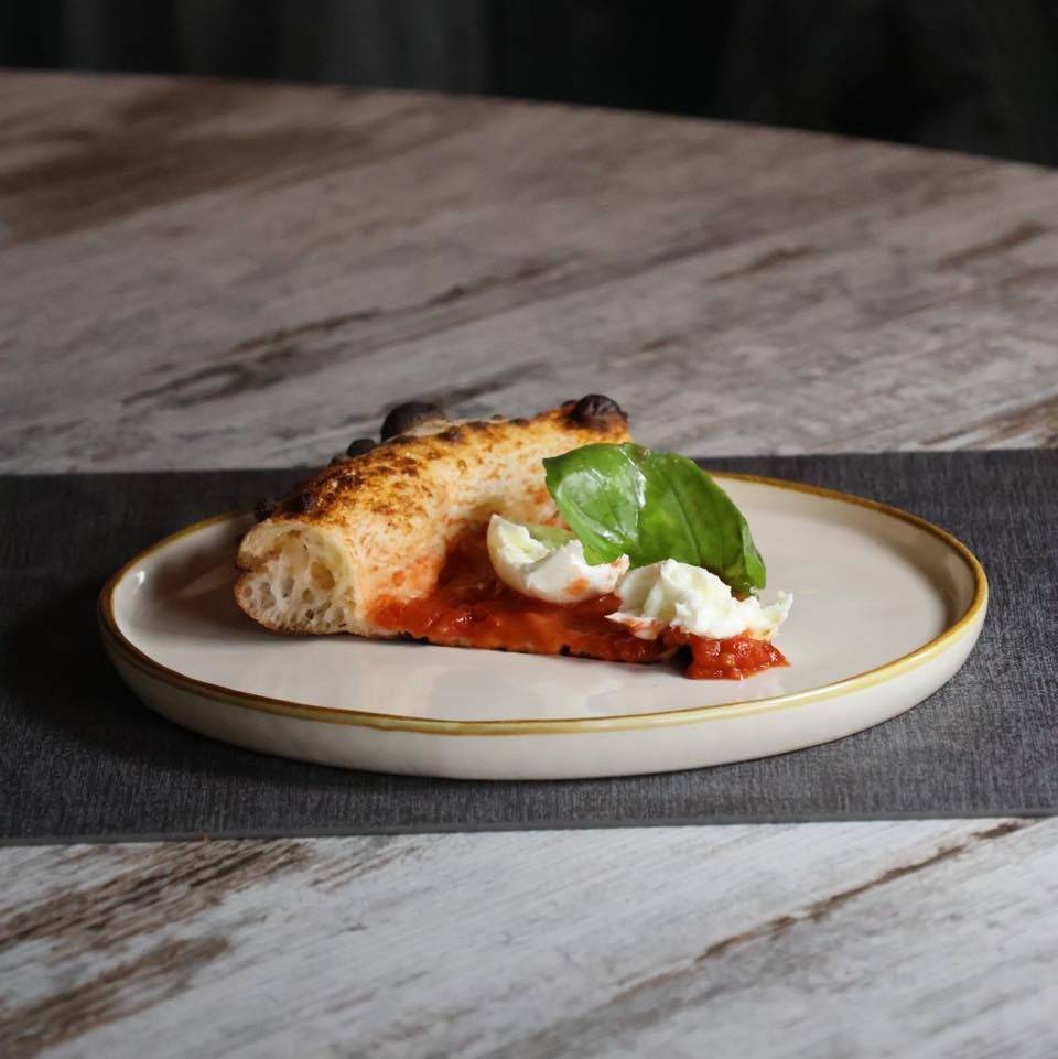 Una fetta di pizza su un piatto bianco su un tavolo.