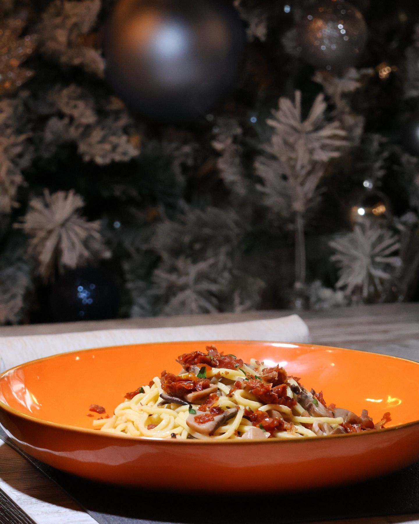 Una ciotola di spaghetti con un albero di Natale sullo sfondo