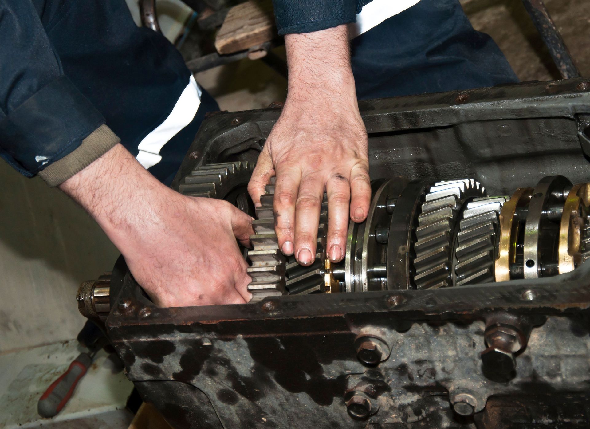 Hands adjusting precision gears inside an open vehicle transmission during mechanical repair work. Hands adjusting precision gears inside an open vehicle transmission during mechanical repair work.