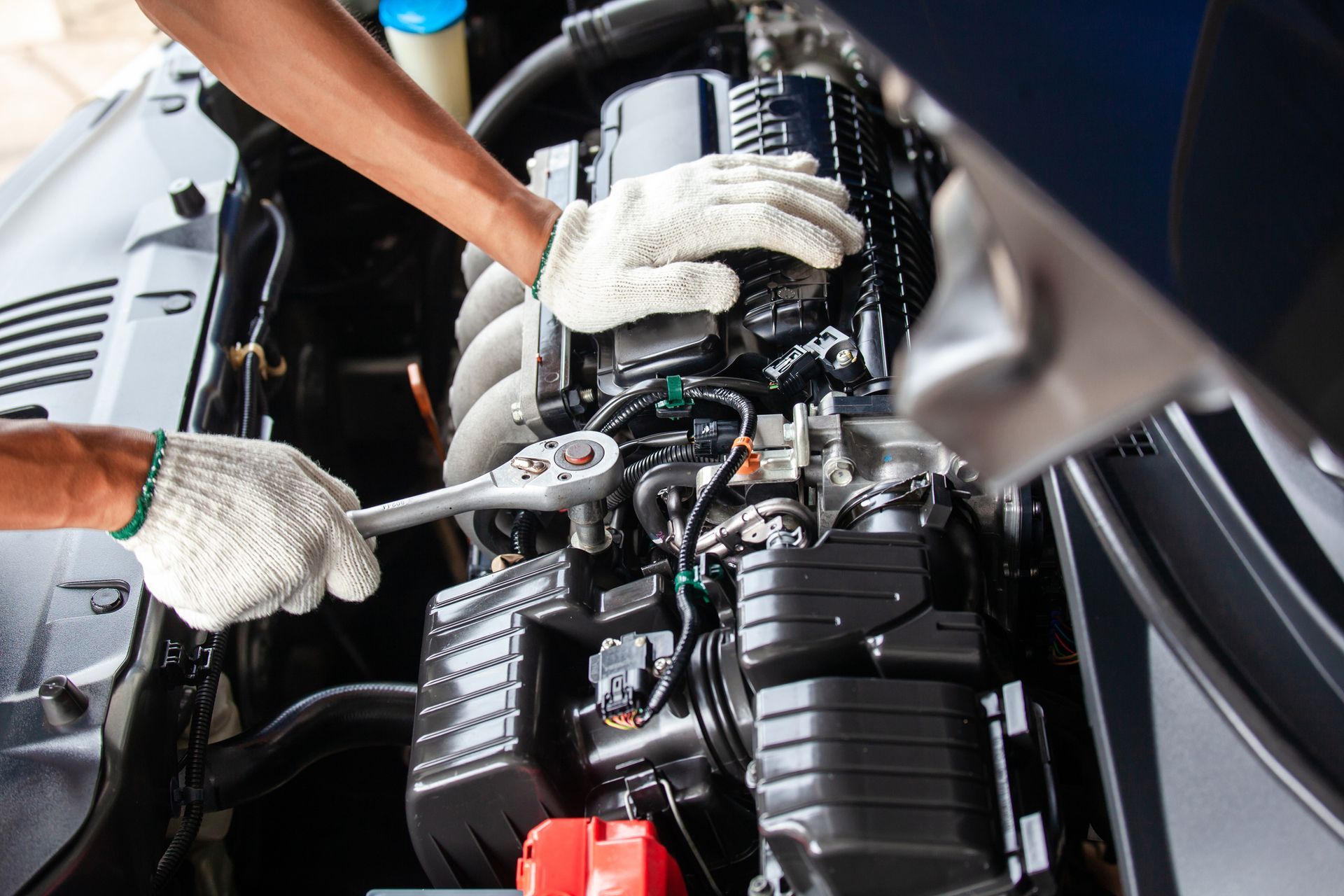 A man is engaged in transmission repair, working diligently on a car's engine components.
