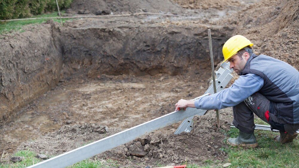 A man is measuring a hole in the ground with a ruler.