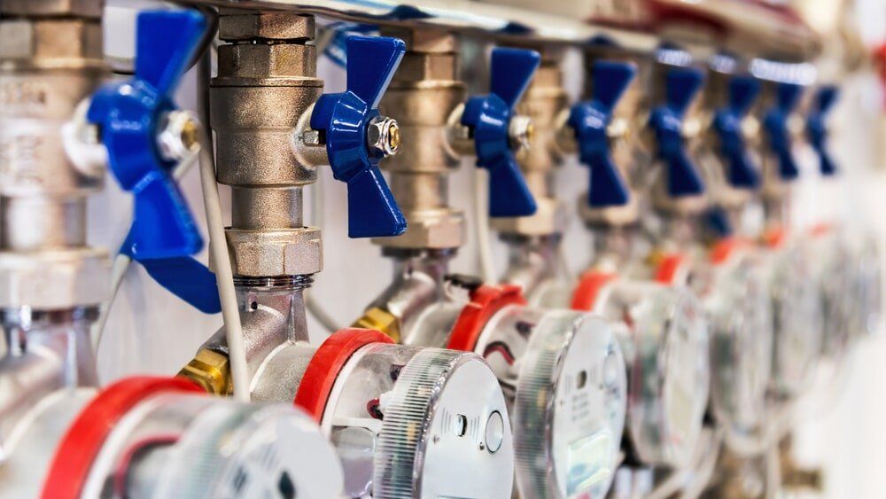 A row of valves with blue handles are lined up in a row.