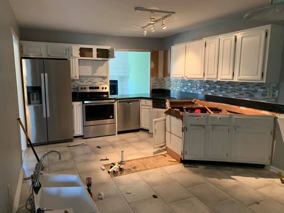 Kitchen under renovation with white cabinets, stainless steel appliances, and tile floor.