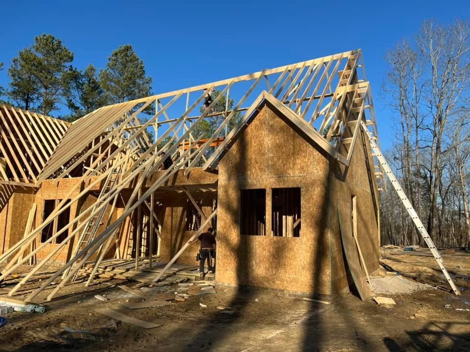House under construction with exposed wooden frame and blue sky.