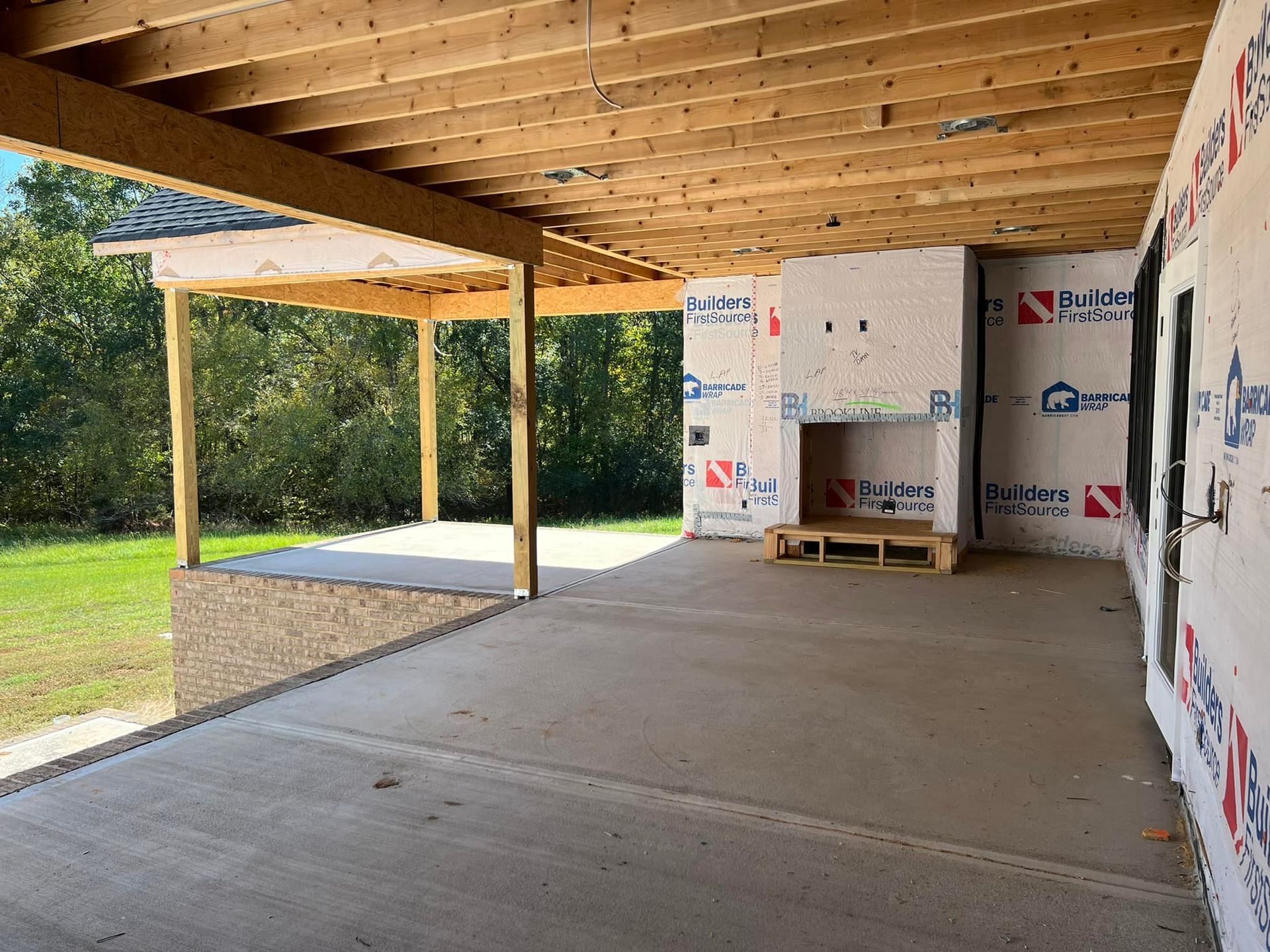 Construction site with a covered patio, fireplace, and unfinished walls.