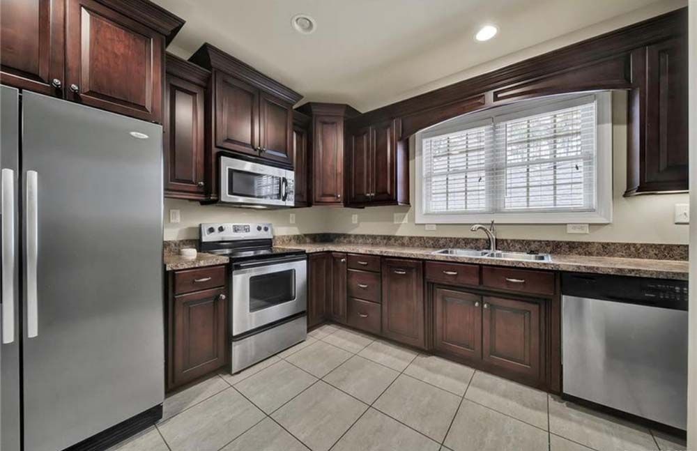 Kitchen with dark brown cabinets, stainless steel appliances, and tiled floor.
