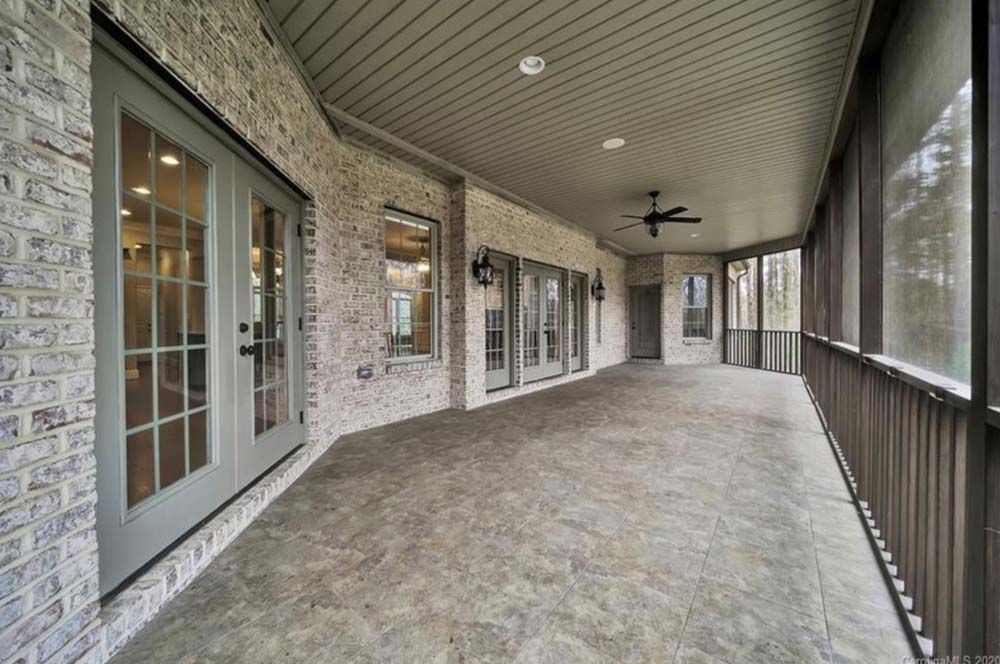 Covered patio with gray brick walls, concrete floor, French doors, and a screened-in section.
