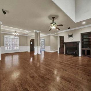 Spacious, empty living room with hardwood floors, fireplace, and built-in shelves.