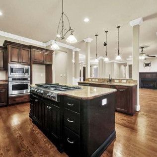 Elegant kitchen with dark cabinets, stainless steel appliances, and a large island with a stove.