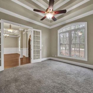 Empty room with gray carpet, French doors, large window, and ceiling fan.