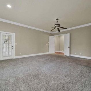 Empty room with gray carpet, light beige walls, white trim, and a ceiling fan.