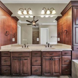 Bathroom with wood cabinetry, double sinks, large mirror, and ceiling fan.