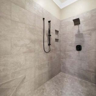 Gray tiled shower with black fixtures and recessed storage.