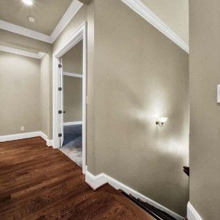 Hallway with hardwood floor, door to a room, and a staircase descending to the right. Beige walls with white trim.