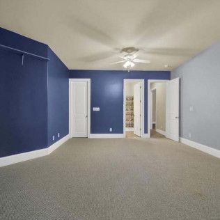 Empty bedroom with blue and gray walls, white doors, and gray carpet.