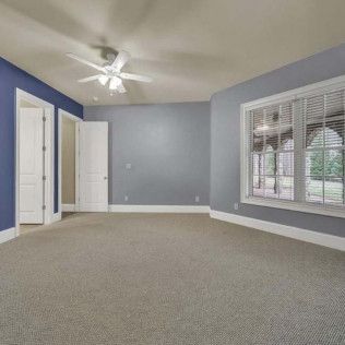 Empty bedroom with blue and gray walls, white trim, and a ceiling fan.