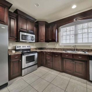 Kitchen with dark wood cabinets, stainless steel appliances, and a window.