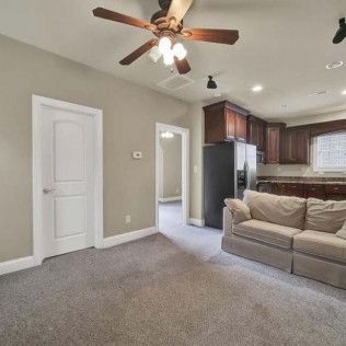 Living room with carpet, a sofa, and an open doorway to a kitchen area.