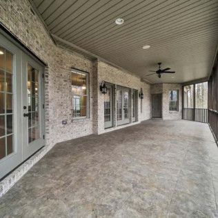 Covered outdoor patio with brick walls, grey doors, and concrete floor.