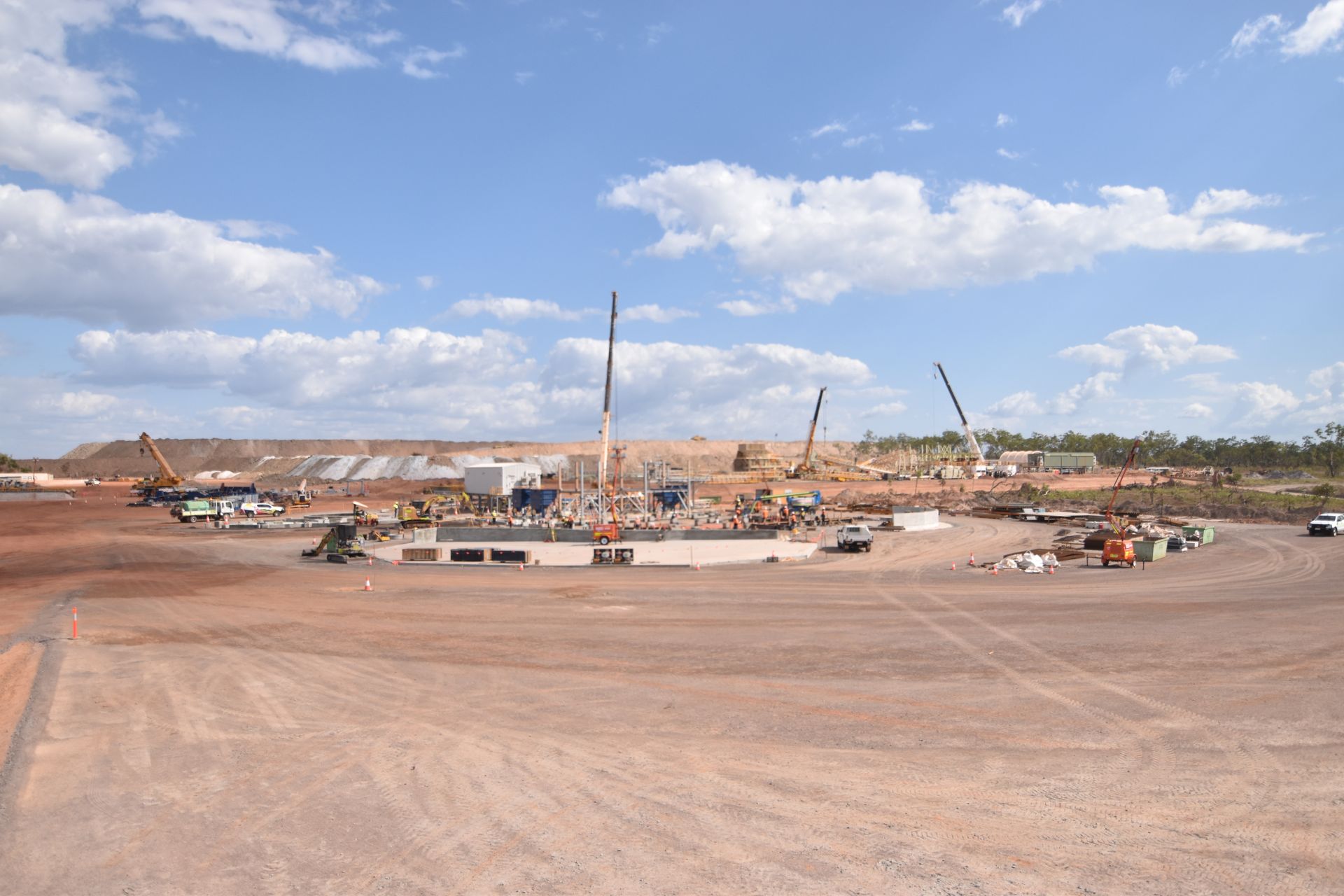 A large construction site with a lot of trucks and cranes.
