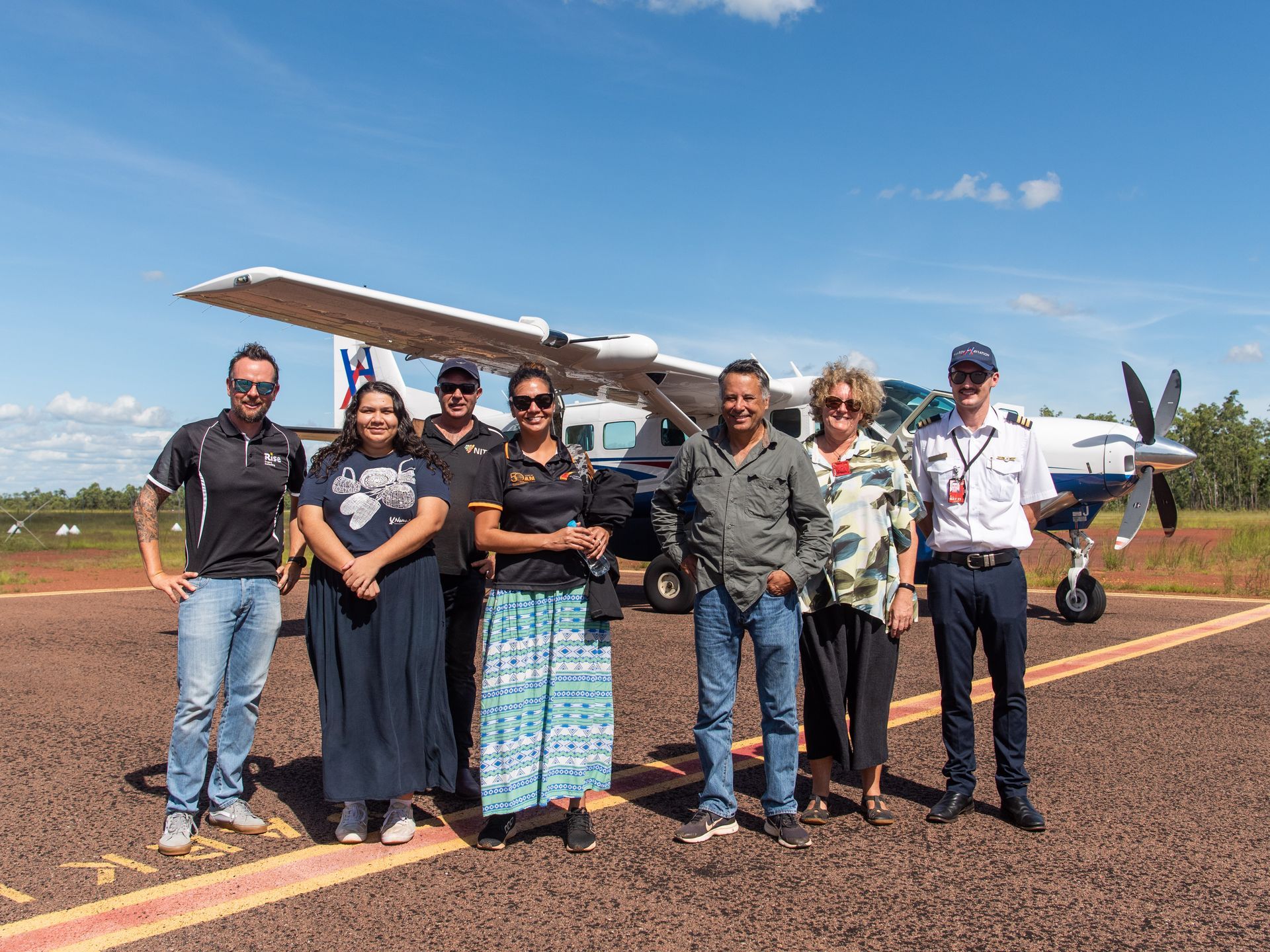 A group of people are standing on a runway in front of a small plane.