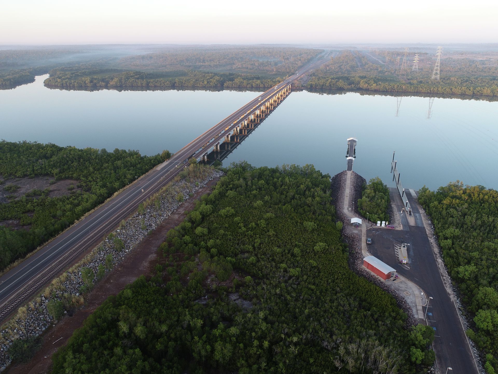 An aerial view of a bridge over a river surrounded by trees.