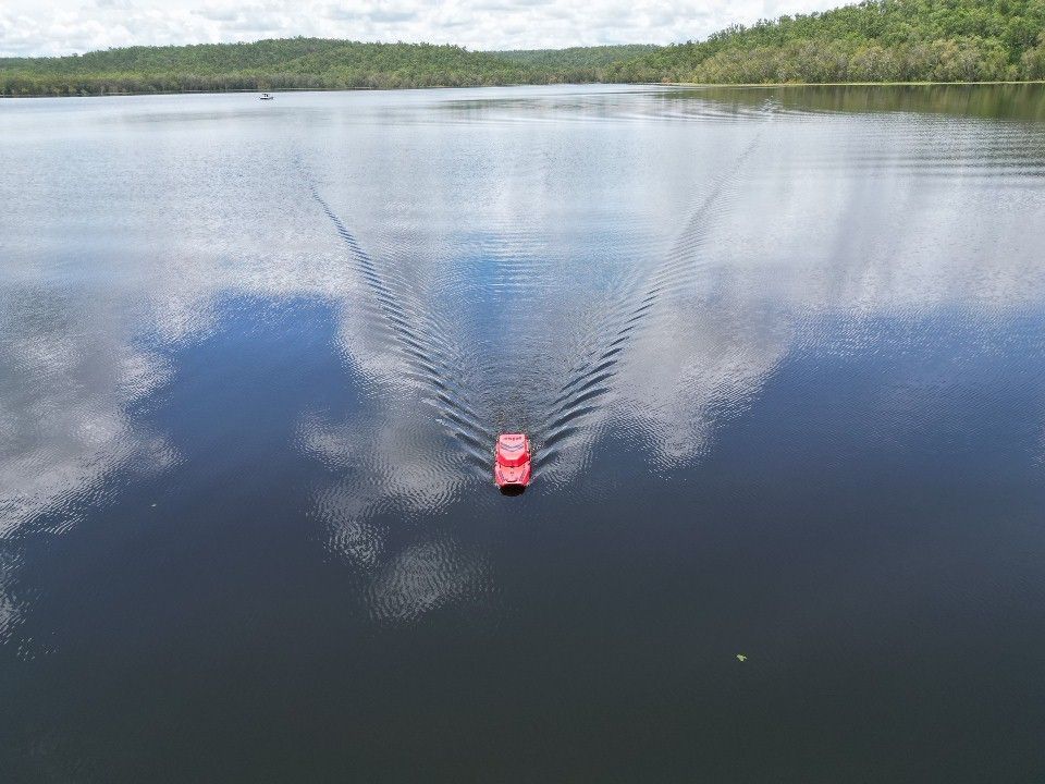 A red boat is floating on top of a large body of water.
