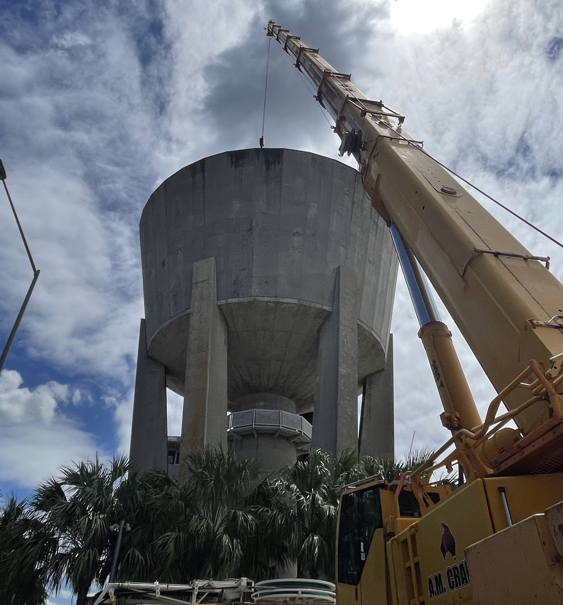 A large yellow crane is lifting a large concrete tower