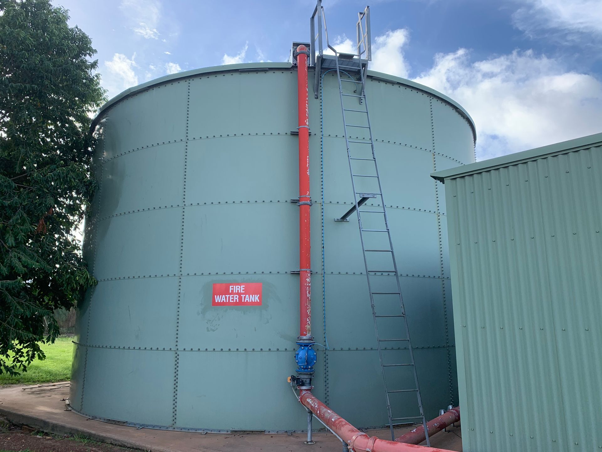 A large water tank with a red pipe attached to it.