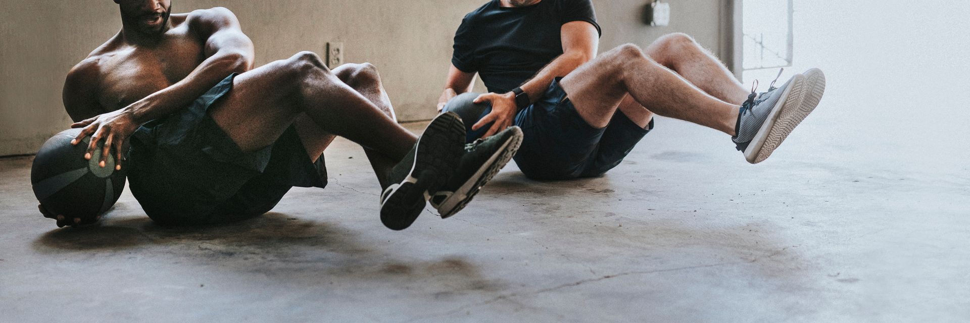 Three men are sitting on the floor doing exercises with a ball.