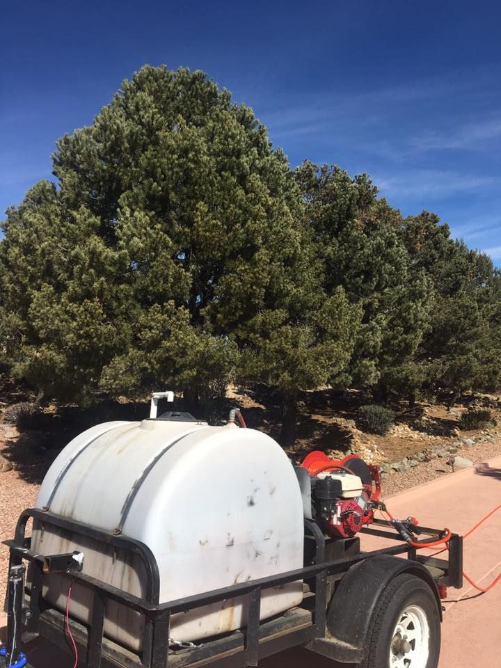 A trailer with a large white tank on it is parked on a dirt road.