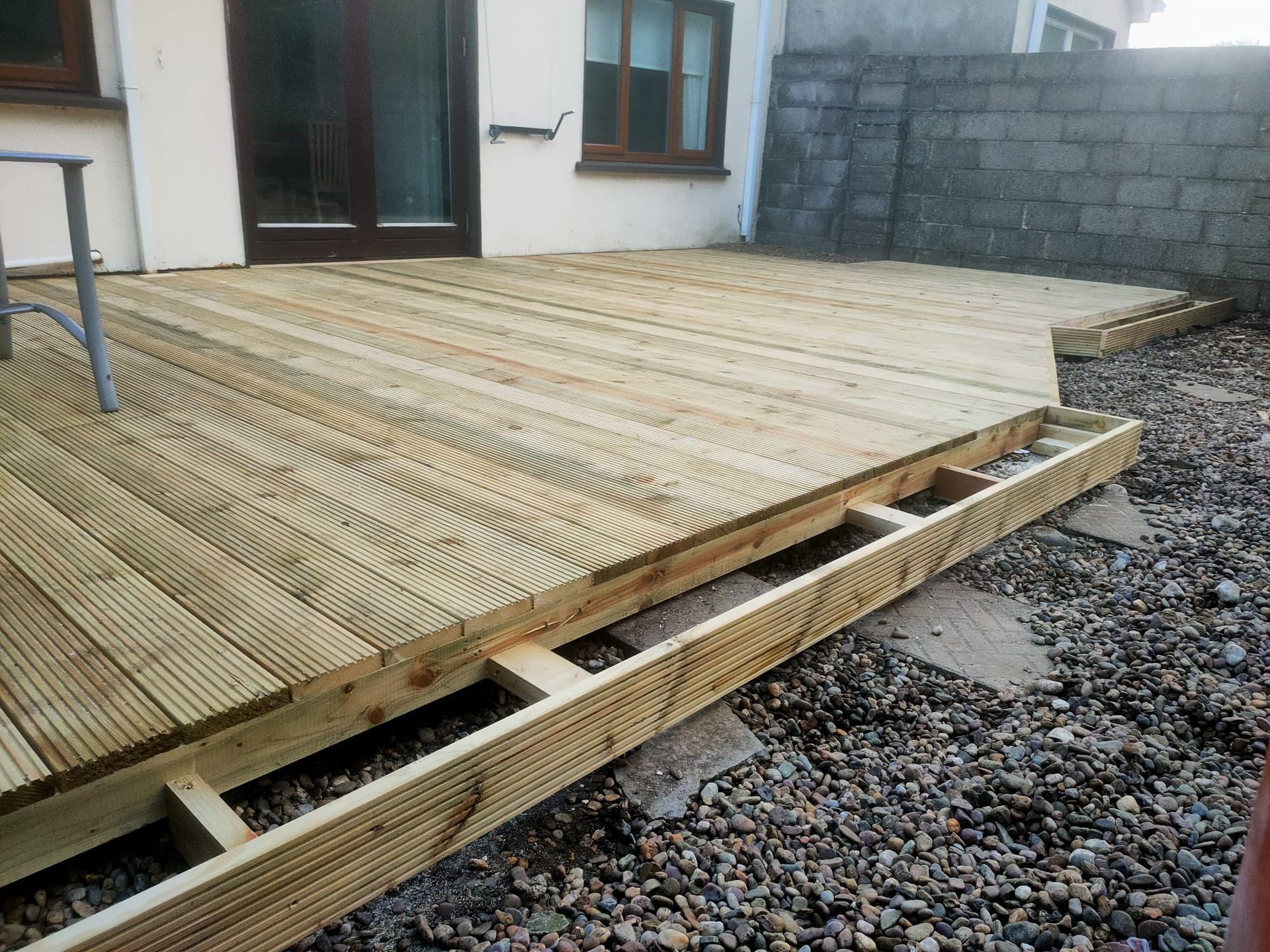 Wooden deck under construction in a yard. Deck boards and frame visible.