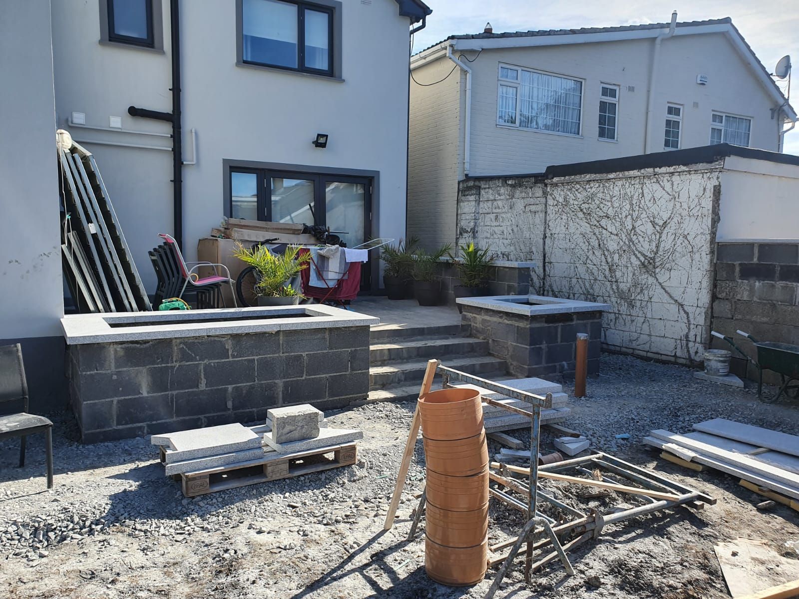 Backyard under construction with block walls, patio, and building materials.