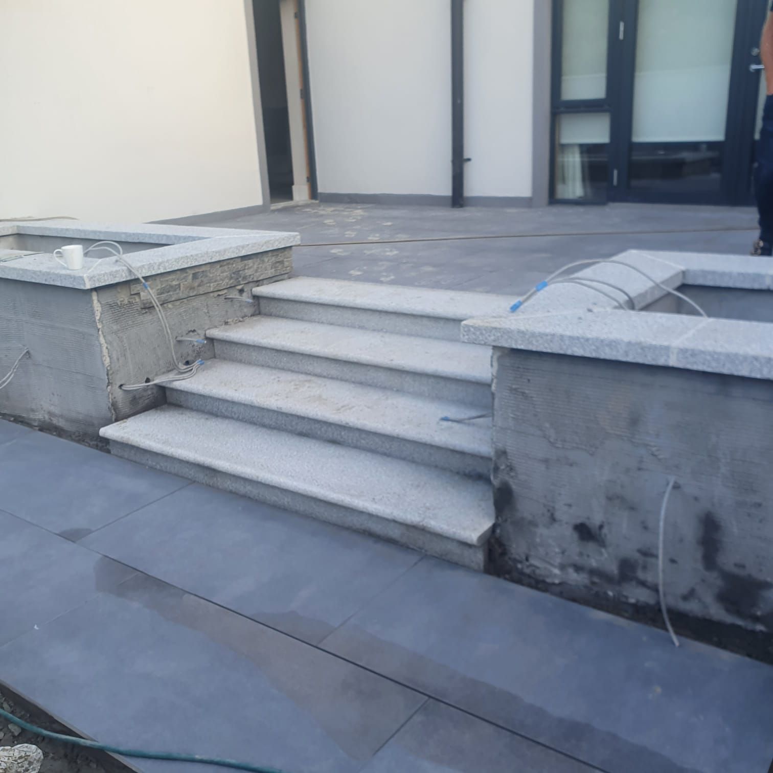 Exterior steps made of light grey stone, leading up from a dark grey patio.