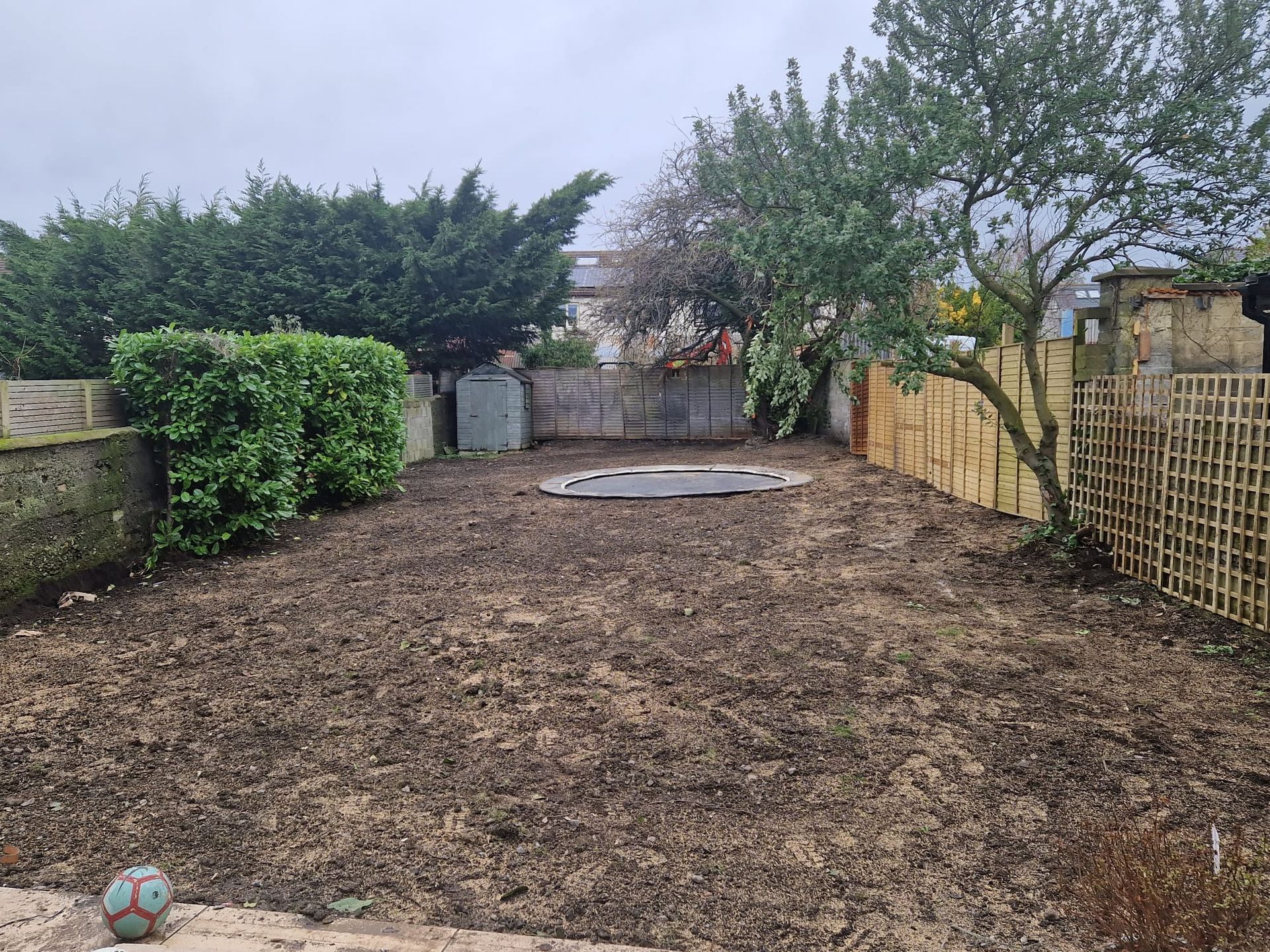 Overhead view of a small backyard: grass lawn, gray brick patio, shed, and brick border.